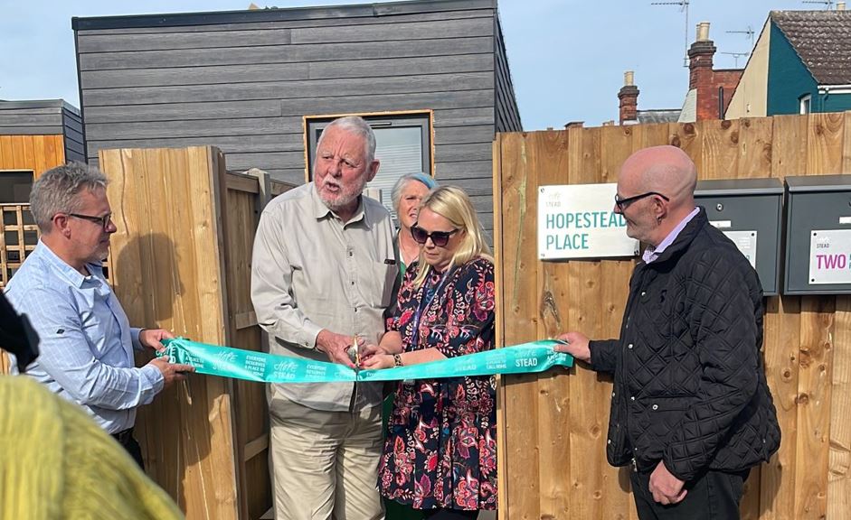 People cutting the ribbon at a shelter unveiling